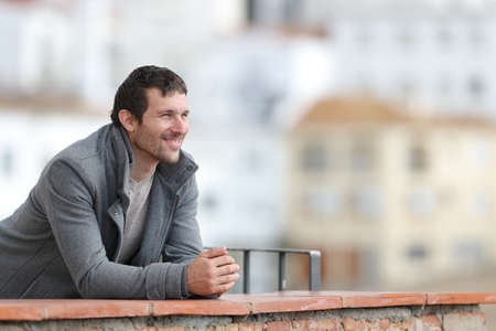 Happy man in winter contemplating views in a balcony in a rural townの写真素材