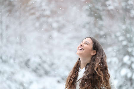 Happy girl breathing fresh air laughing enjoying snow in winter in the mountainの写真素材