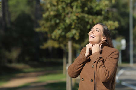 Happy woman warmly clothed in winter breathing fresh air standing in a parkの写真素材