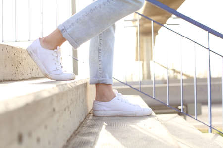 Profile close up of woman legs wearing sneakers walking down stairsの写真素材