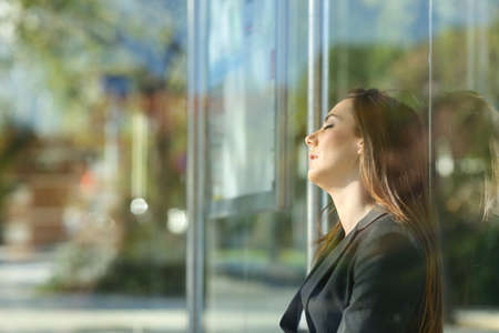 Side view portrait of a tired executive sleeping waiting in a bus stopの写真素材