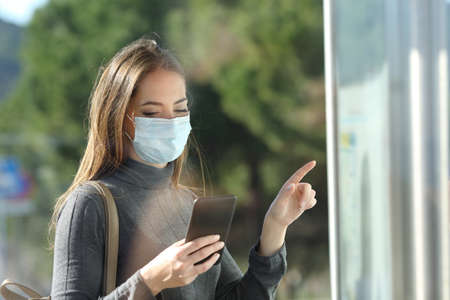 Commuter with a protective mask avoiding contagion checking bus scheduleの写真素材