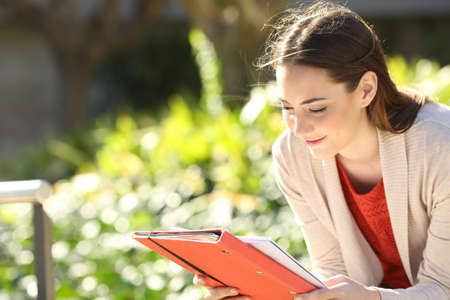 Studious student reading notes studying sitting in a park or university campus