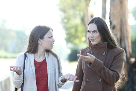 Front view portrait of two angry women arguing in a park in winterの写真素材