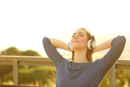 Relaxed young woman listening to music and meditating outdoors in the natureの写真素材
