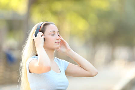 Concentrated teenage girl listening to music with a park background at summerの写真素材