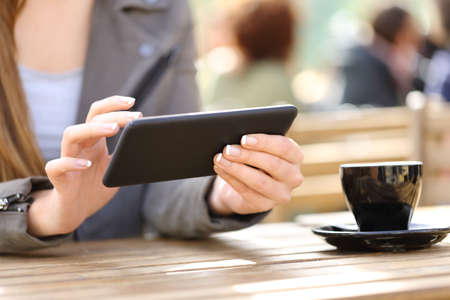 Close up of woman hands watching videos on her smart phone on a cafe terraceの写真素材