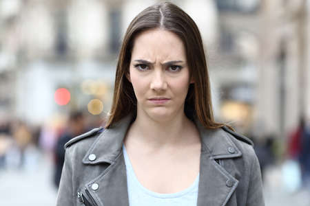 Front view portrait of an angry woman looking annoyed at camera on city streetの写真素材