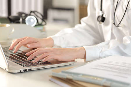 Close up of doctor woman hands typing on laptop siting on a desk at the officeの写真素材