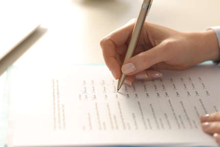 Close up of executive woman hand filling out form on a desk at the officeの写真素材