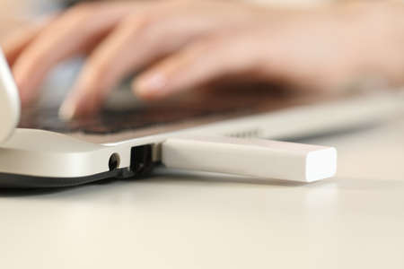 Close up of woman hands working on laptop with plugged pendrive on foreground on a deskの写真素材