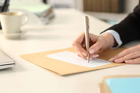 Close up of business woman hand filling out bank check sitting on a desk at the officeの写真素材