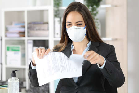Executive woman wearing protective mask ripping contract on a desk at the officeの写真素材