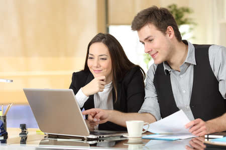 Satisfied office workers checking laptop online content at officeの写真素材