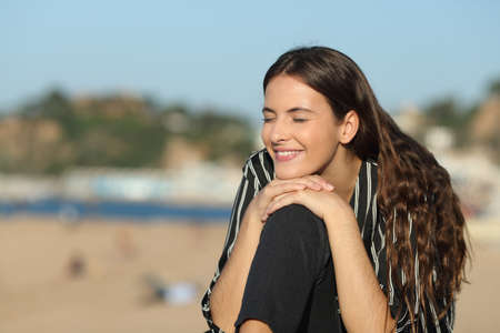 Happy girl closing eyes resting sitting on the beach a sunny dayの写真素材
