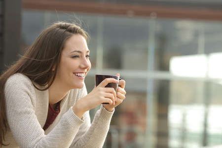 Happy woman drinking coffee in an apartment balcony on vacationの写真素材