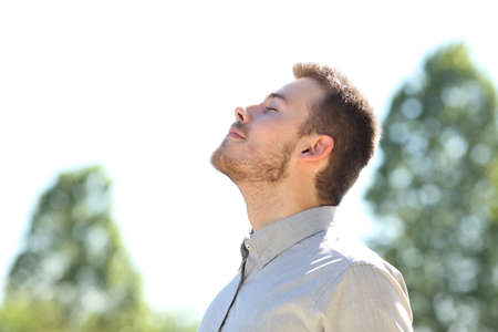 Side view of a man breathing fresh air standing outdoors on a green parkの写真素材