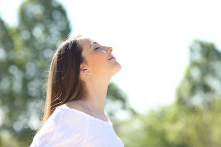 Side view of a relaxed woman breathing fresh air standing outdoors on a green parkの写真素材