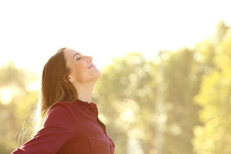 Relaxed woman breathing fresh air outdoors standing outstretching arms on a parkの写真素材
