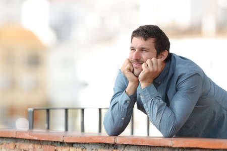 Pensive man contemplating and thinking on a balcony on a town