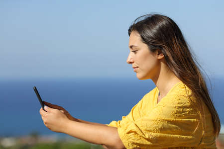 Side view portrait of a serious woman using phone in a hotel balcony on summer vacationの写真素材