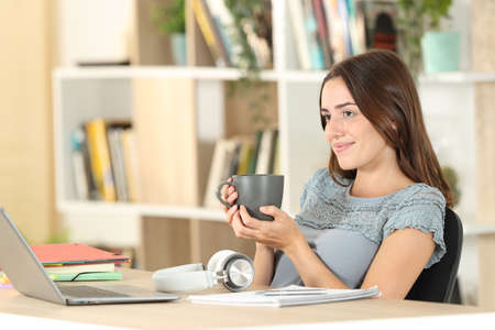 Relaxed student resting drinking coffee contemplating sitting at homeの写真素材