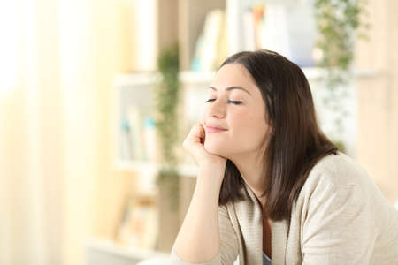 Satisfied woman relaxing mind sitting on a couch in the living room at homeの写真素材