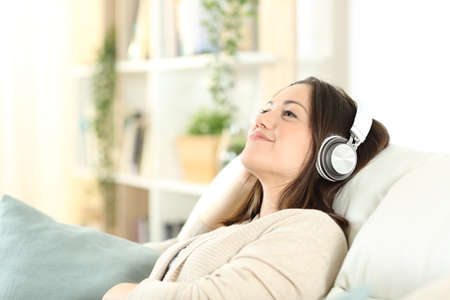 Satisfied woman relaxing sitting on a sofa listening to music at homeの写真素材