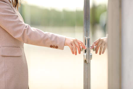 Close up of a businesswoman hand arriving at work opening door in the streetの写真素材