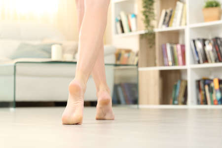 Back view of beauty woman legs and feet walking on the floor in the living room at homeの写真素材