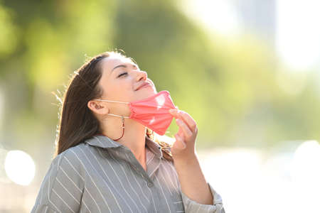 Happy woman taking off mask breathing fresh air outdoors in a parkの写真素材