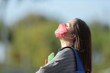 Profile of student with protective mask breathing fresh air avoiding coronavirus contagion in a park