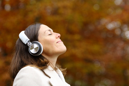 Adult woman breathing fresh air with headphones in a park in autumnの写真素材