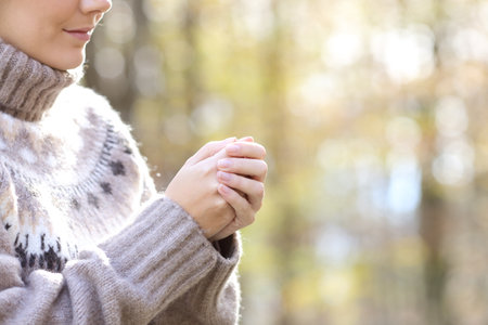 Close up of woman heating hands in a cold winter in a parkの写真素材