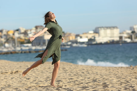 Full body portrait of a happy woman wearing dress celebrating summer vacation on the beachの写真素材