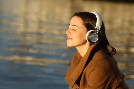 Profile of a woman meditating listening music with headphones in winter on the beachの写真素材