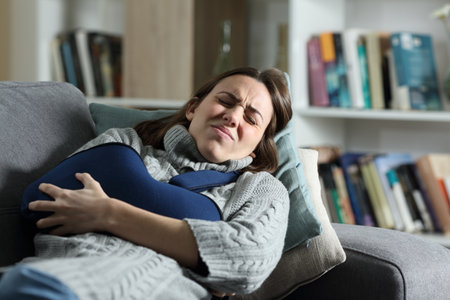 Woman suffering ache with broken arm in a sling lying on a couch at homeの写真素材
