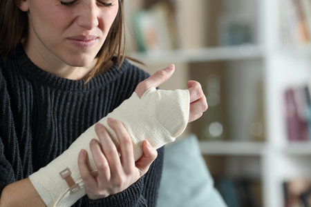 Sad injured woman complaining wearing bandaged arm in the living room at home