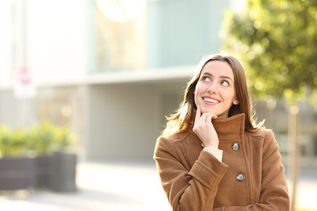 Portrait of a happy woman in winter in the street thinking looking at side with copy spaceの写真素材