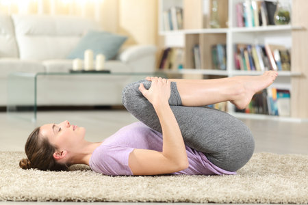 Profile of a concentrated woman doing yoga exercise on the floor at homeの写真素材