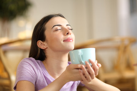 Happy woman smelling coffee breathing fresh air at homeの写真素材