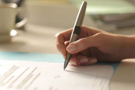 Profile close up of a woman hand singing paper contract at officeの写真素材