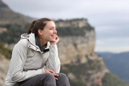 Happy trekker contemplating views sitting outdoors in the mountainの写真素材
