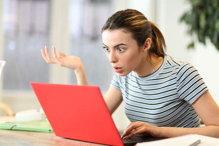Stunned student watching laptop content complaining at homeの写真素材