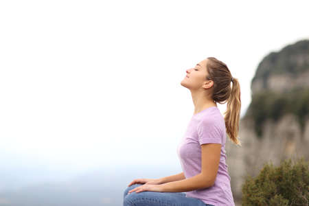 Side view portrait of a woman sitting breathing fresh air in the mountainの写真素材