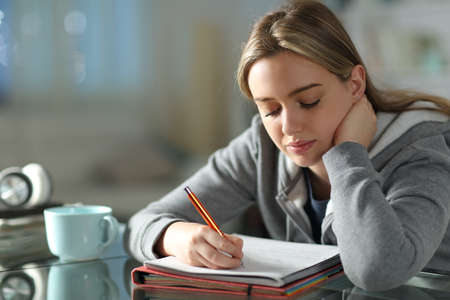 Student learning taking notes in the night in the living room at home
