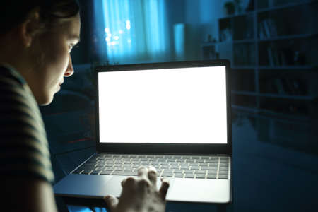 Close up of a woman using and showing blank laptop screen in the night at homeの写真素材