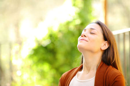 Relaxed woman breathing fresh air in a garden a sunny day at homeの写真素材