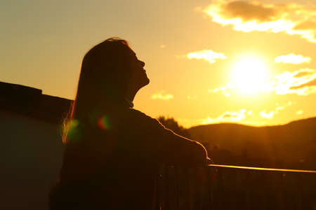 Backlight tenant silhouette breathing fresh air in a balcony at sunsetの写真素材