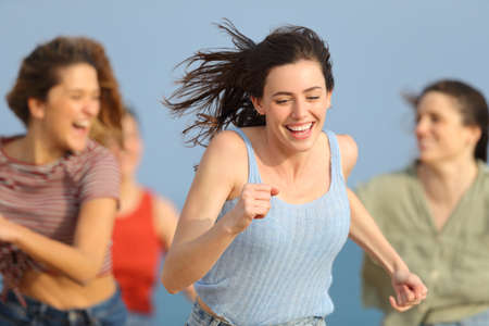 Front view of happy friends running on summer on the beachの写真素材